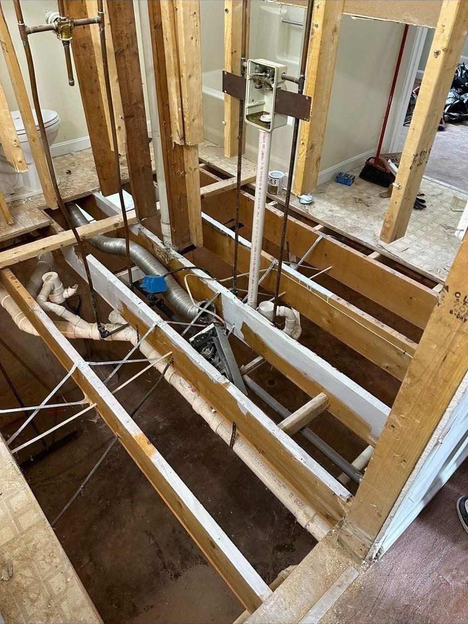 Open subfloor and plumbing exposed during a water damage repair job